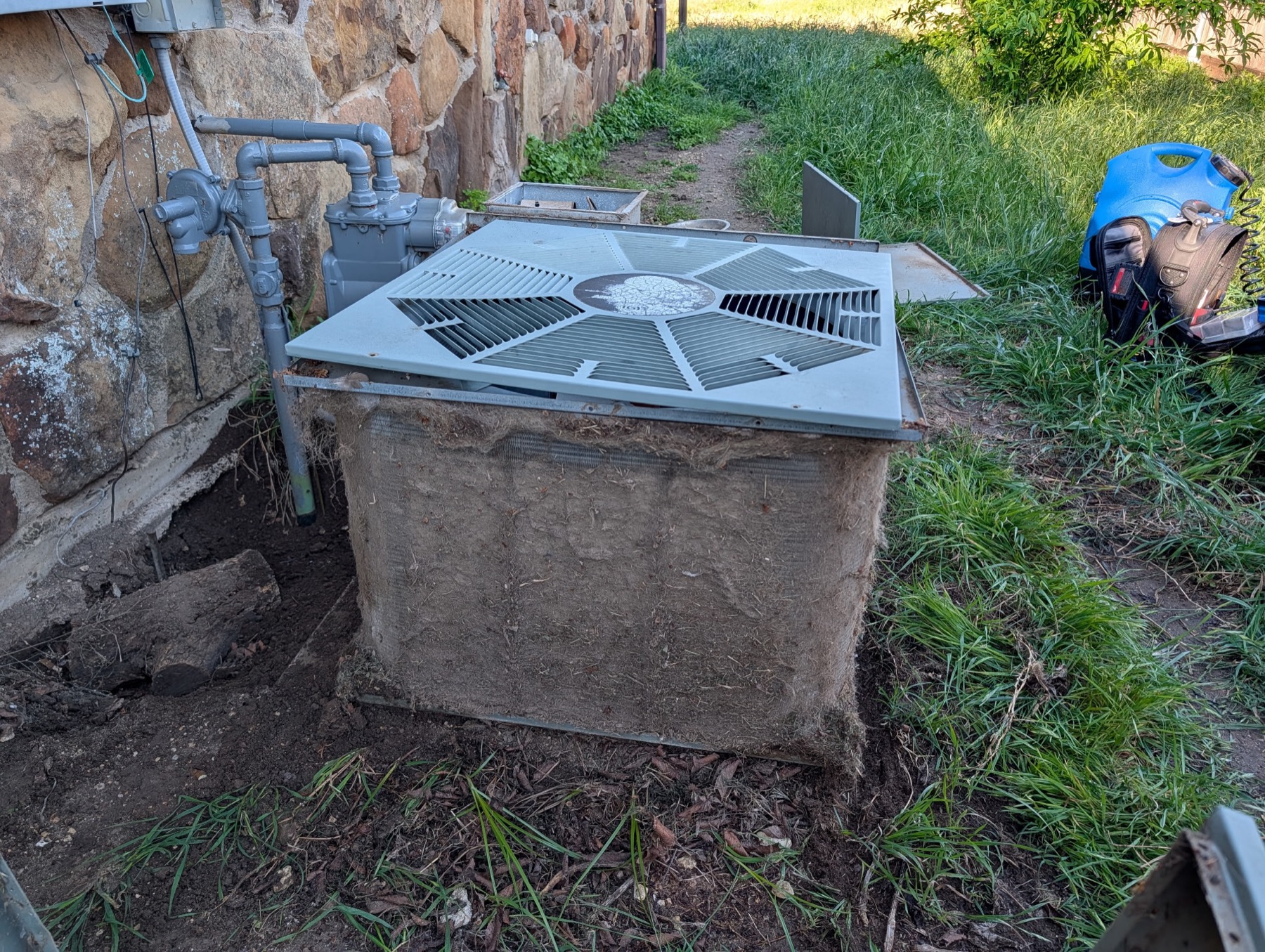 Condenser and gas piping beside a stone foundation at a rural Van Wyck area property serviced by EZ Heating and Cooling