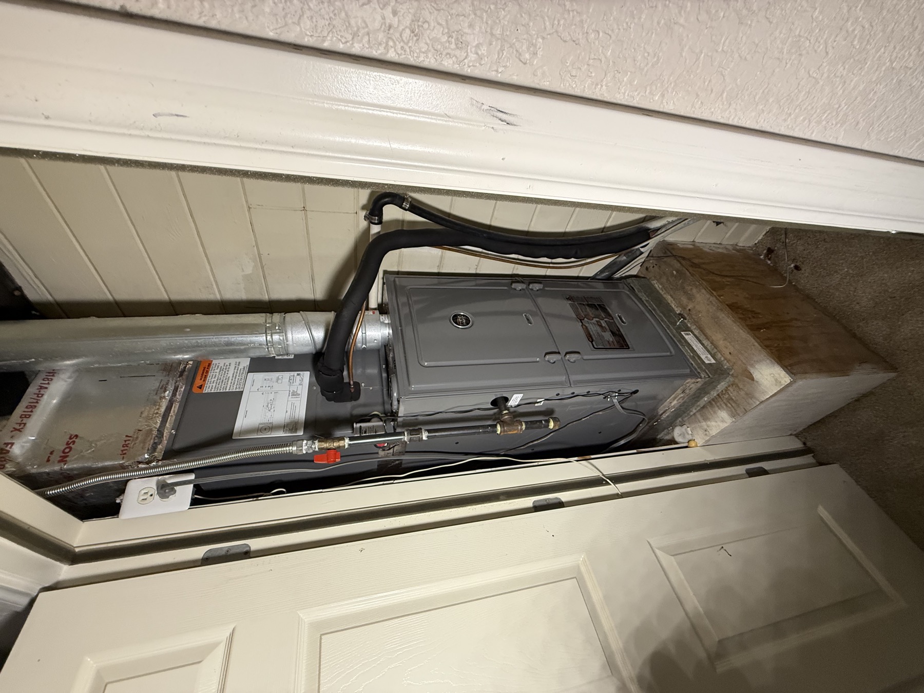 New gas furnace on a platform in a hallway closet, vent pipe rising from the top and the gas line on the left