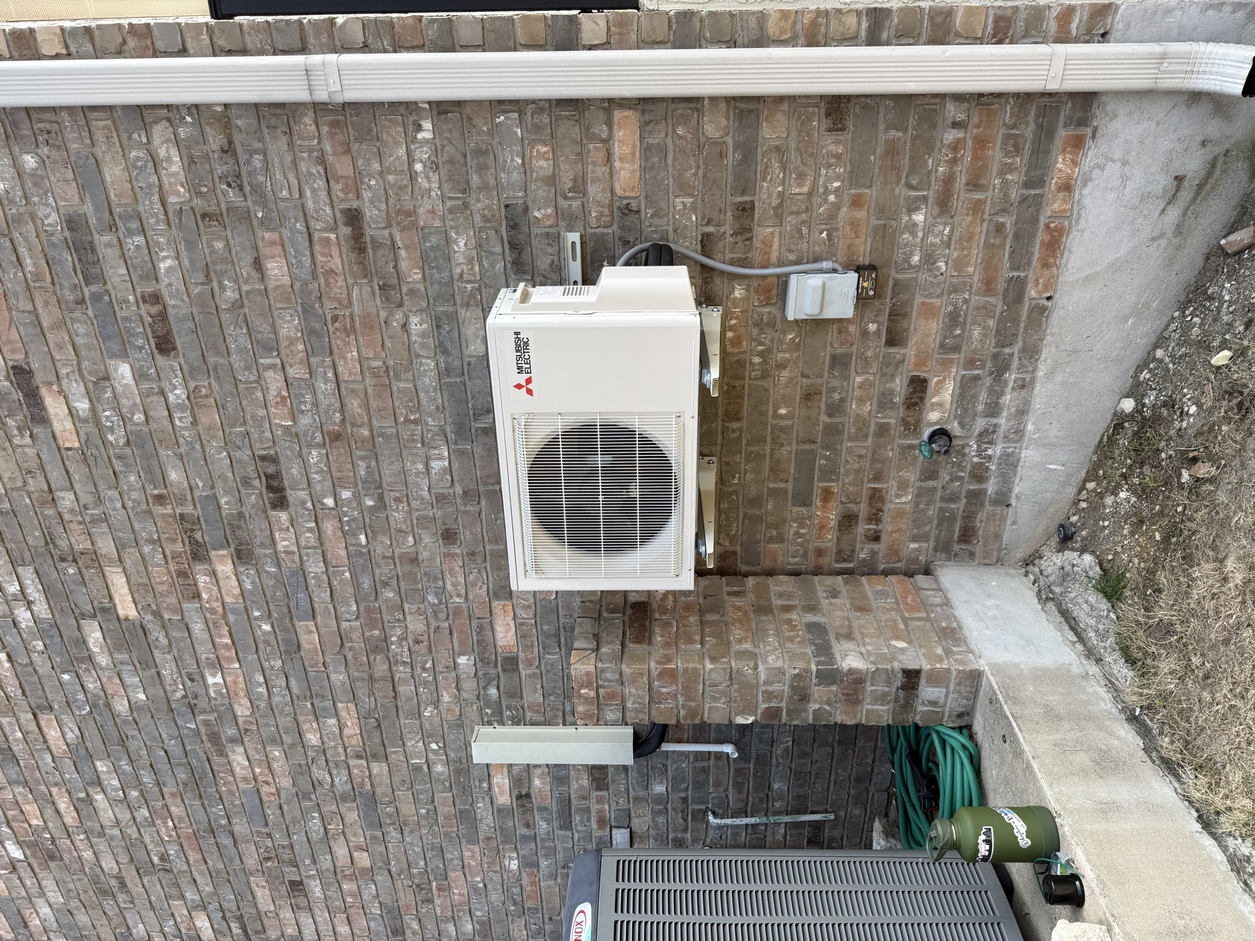 Mitsubishi ductless mini split outdoor unit mounted on a brick wall by EZ Heating and Cooling