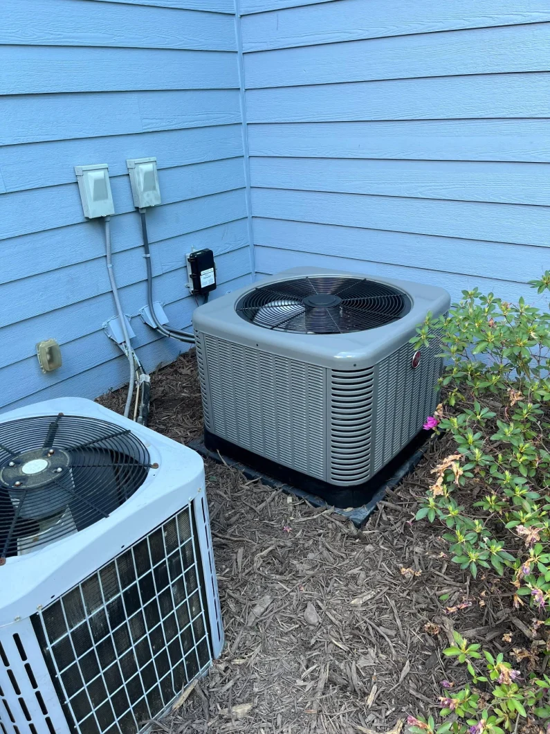 New Rheem condenser installed beside a blue-sided home by EZ Heating and Cooling